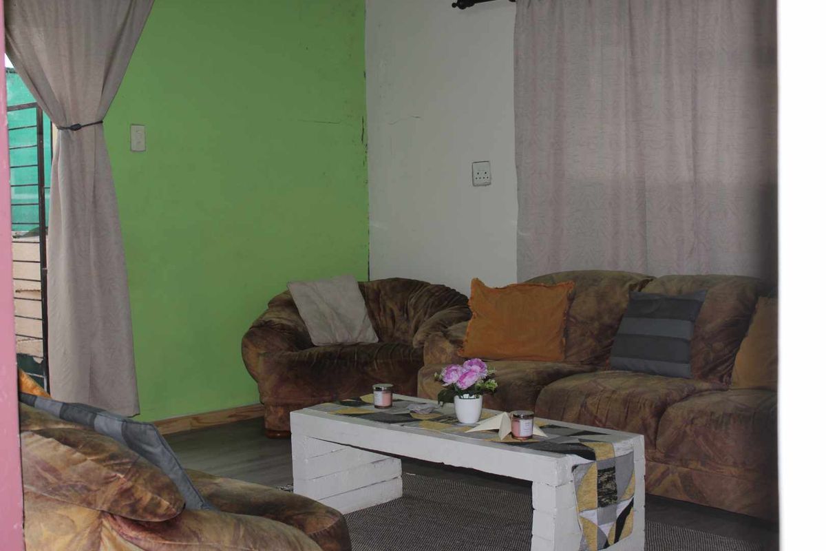 A living room area featuring laminate flooring and painted walls, currently furnished with a seating arrangement.