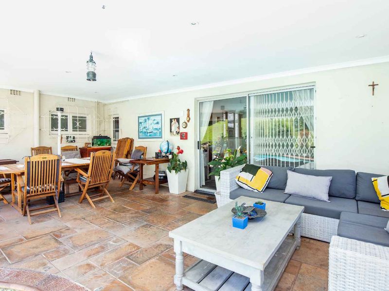 Spacious covered patio featuring durable tiled flooring and sliding glass doors, providing a seamless transition to the outdoor pool area.