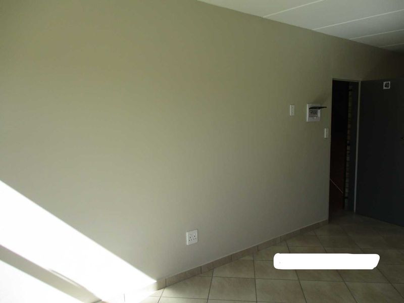 A clean, empty entrance area featuring neutral wall tones, tiled flooring, and an installed intercom system.