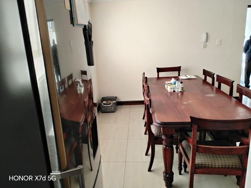 A functional dining area featuring neutral tiled flooring and a wall-mounted intercom system, providing a practical space for meals.