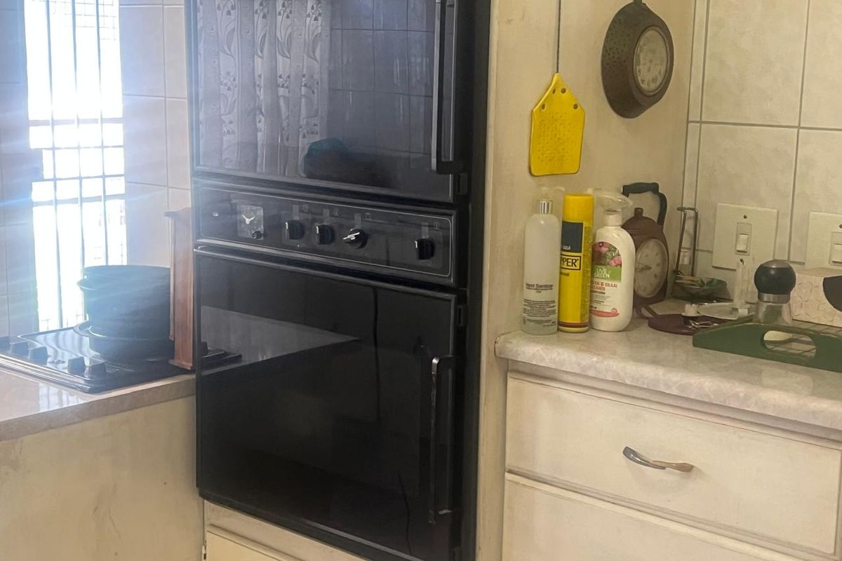 A functional kitchen area featuring a built-in double oven, cooktop, and tiled backsplash with laminate countertops and traditional cabinetry.