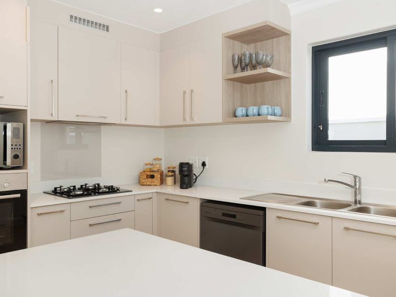 Modern kitchen featuring sleek cabinetry, stone countertops, gas hob, built-in oven, and integrated appliances with a clean, contemporary finish.