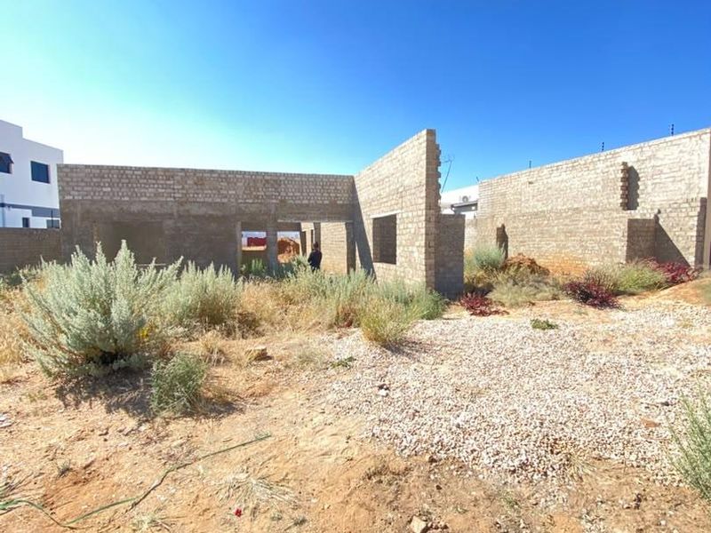 An unfinished residential construction site showing the brick masonry shell of a property in the early stages of development.
