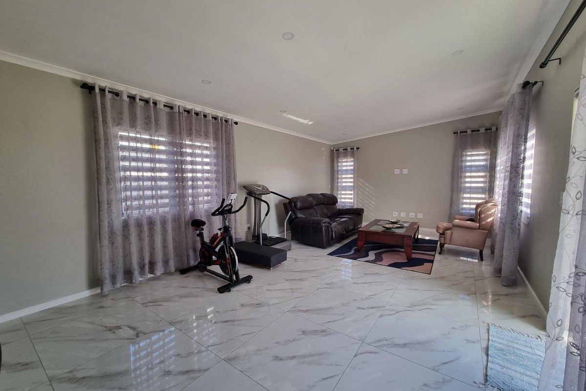 Spacious living area featuring polished marble-look porcelain floor tiles, recessed downlighting, and neutral wall finishes, offering a bright and versatile open-plan space.