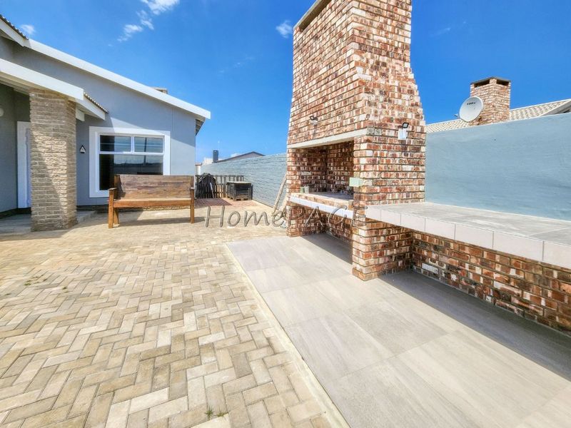 Outdoor patio area featuring a built-in brick braai, tiled prep surface, and paved flooring, ideal for outdoor entertaining.