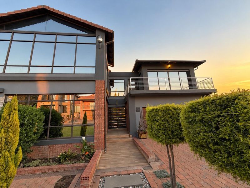Modern double-storey residence featuring a striking combination of brick and dark-toned exterior finishes, large glass windows, and a welcoming timber-decked entrance.