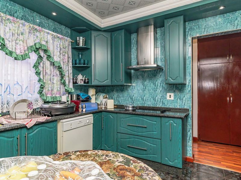 A dated kitchen featuring teal cabinetry, tiled walls, built-in oven, and extractor fan, offering significant potential for a modern renovation.