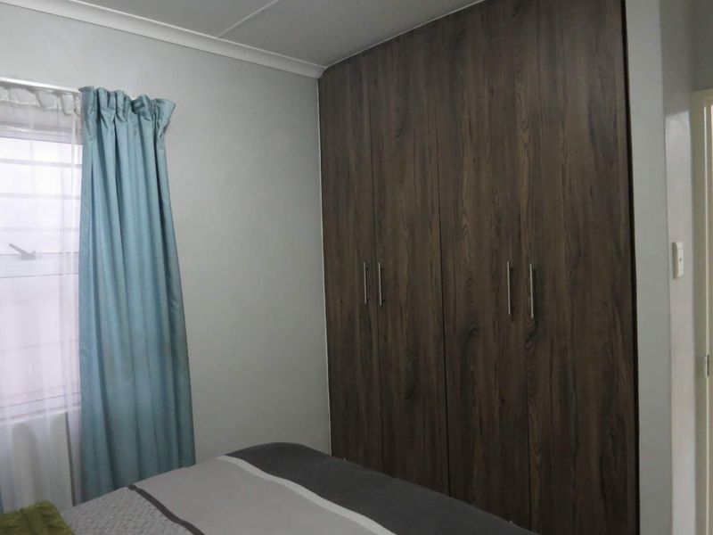 A bedroom featuring dark wood-finish built-in cupboards and neutral wall tones.