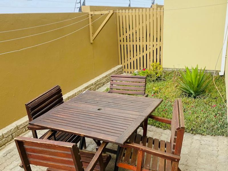 A private rear courtyard featuring paved flooring, a boundary wall with electric fencing, and a timber gate.