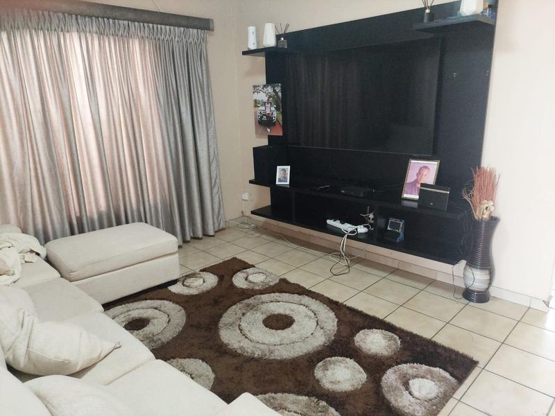 A living room featuring tiled flooring and a large built-in black media unit with shelving.