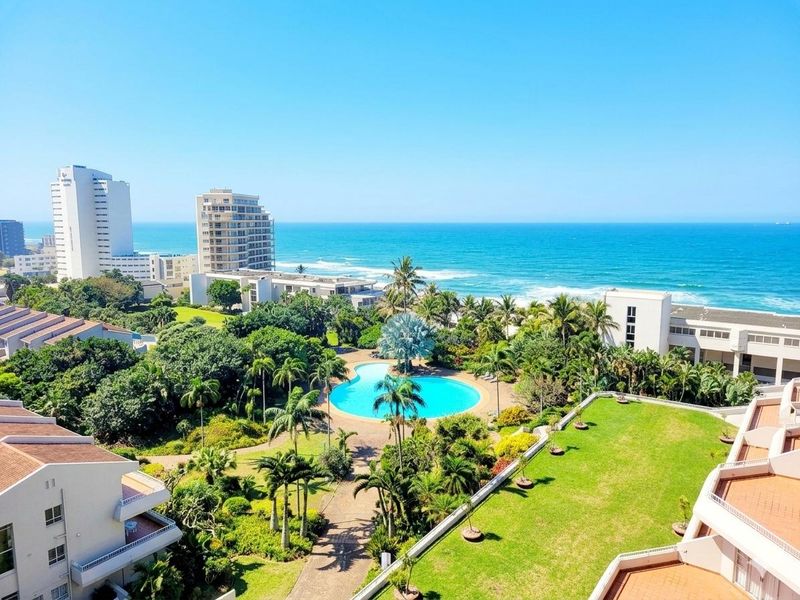 Elevated panoramic view overlooking the complex swimming pool, lush landscaped gardens, and the ocean coastline.