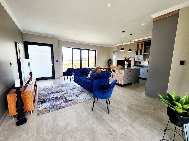Spacious open-plan living area featuring modern tiled floors, recessed lighting, and a contemporary kitchen island, seamlessly connecting to the outdoor space via sliding doors.