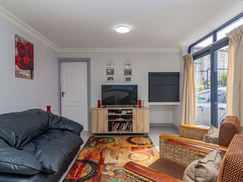 A comfortable living room featuring neutral walls, cove molding, and a large sliding glass door providing natural light and access to the exterior.