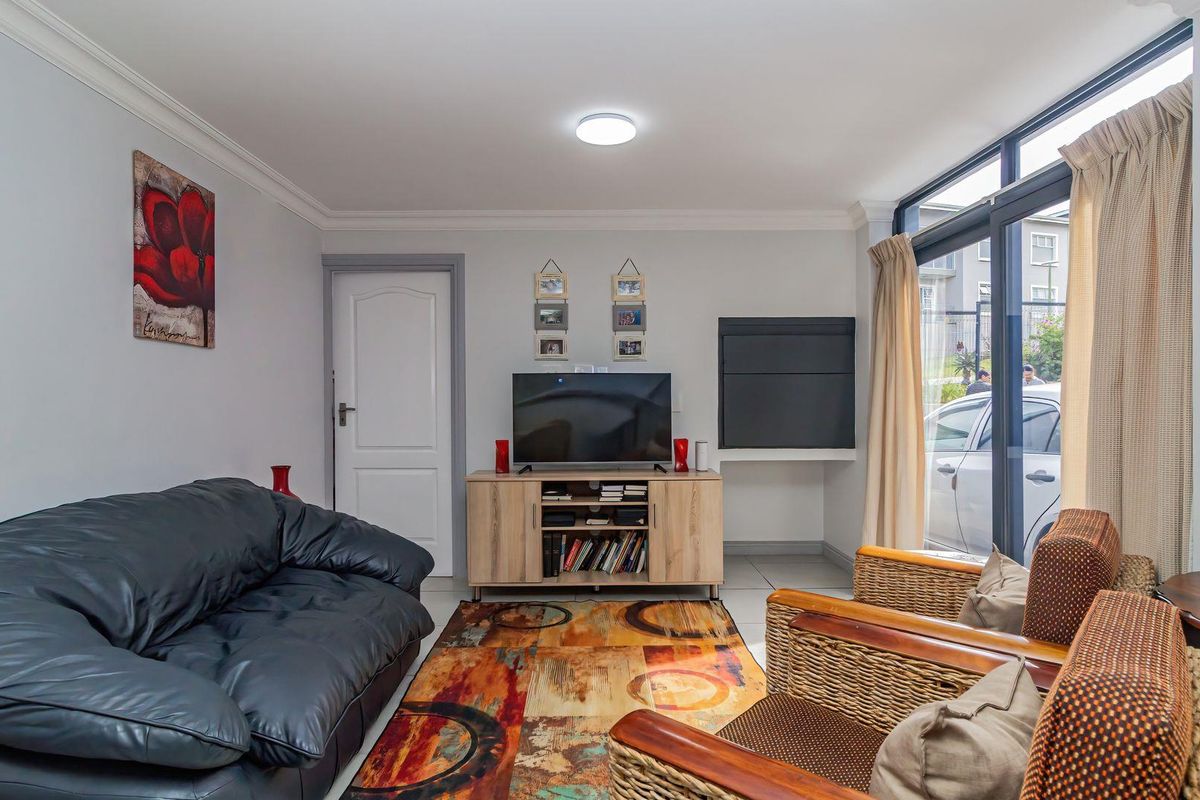 A comfortable living room featuring neutral walls, cove molding, and a large sliding glass door providing natural light and access to the exterior.