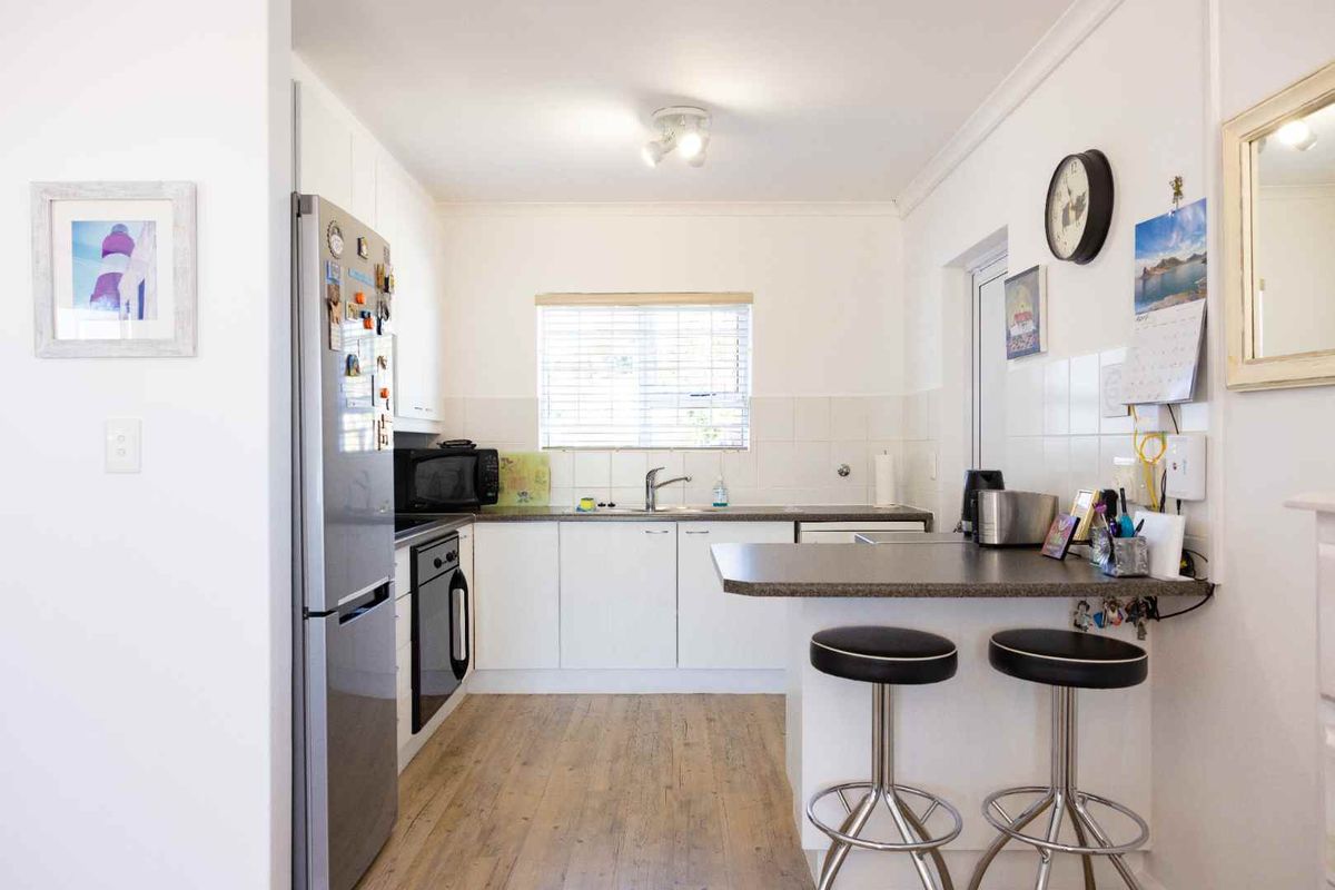 A functional kitchen featuring white cabinetry, laminate countertops, a breakfast bar, and a tiled backsplash with integrated oven and sink.