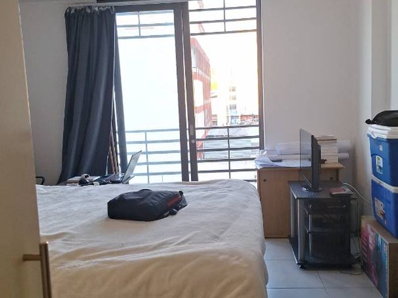 A bedroom featuring tiled flooring, track lighting, and a sliding glass door providing access to a balcony.