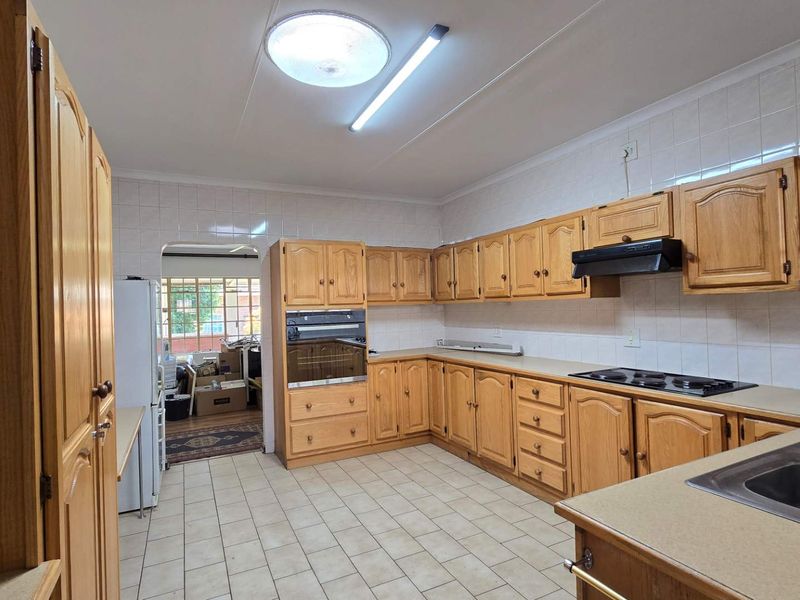 Functional kitchen featuring timber cabinetry, built-in oven, electric hob, extractor fan, and tiled splashbacks with ample storage space.