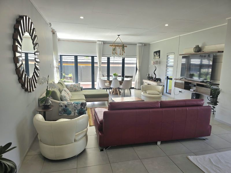Spacious open-plan living and dining area featuring tiled flooring, recessed lighting, and large sliding glass doors leading to the outdoor space.