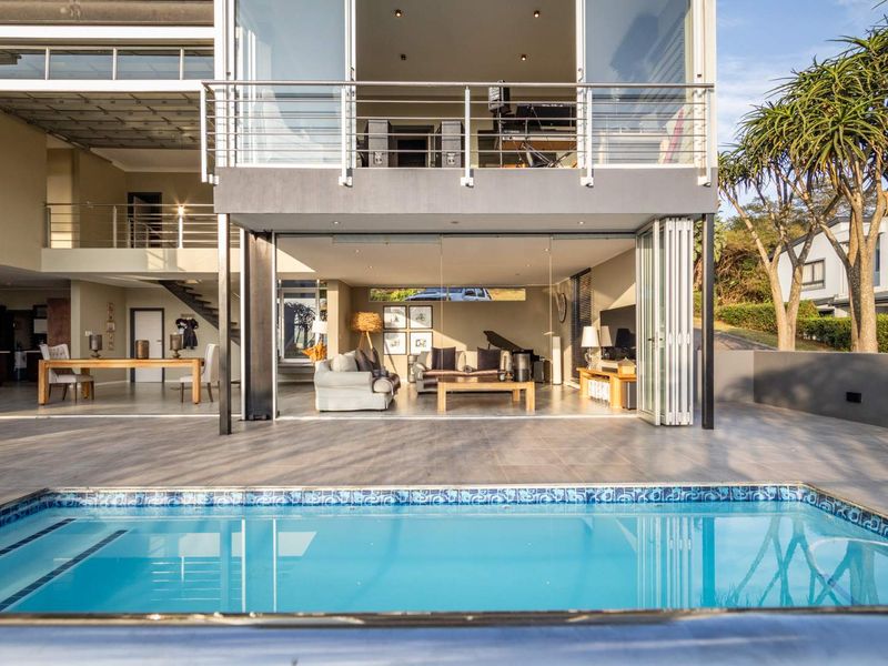 Modern multi-level home featuring a swimming pool, expansive tiled patio, and seamless indoor-outdoor flow through large bi-fold glass doors.