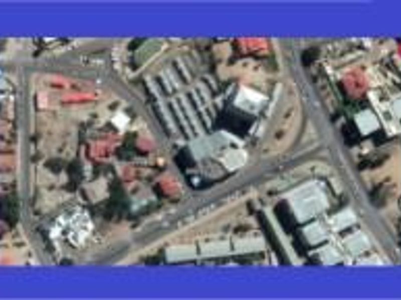 An aerial view showing the surrounding commercial area and street layout of the vacant land property.