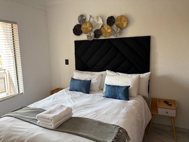 A well-maintained bedroom featuring tiled flooring and venetian blinds, providing a clean and functional living space.