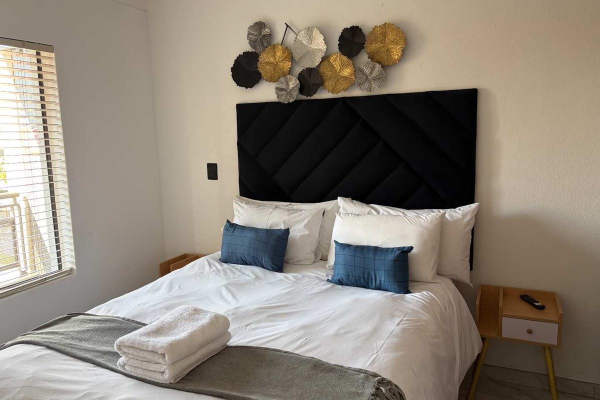 A well-maintained bedroom featuring tiled flooring and venetian blinds, providing a clean and functional living space.