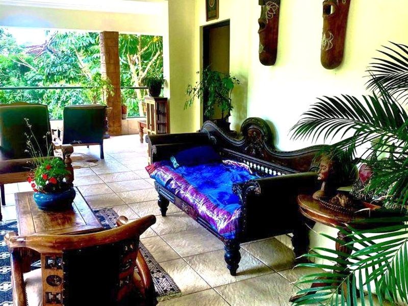A living area featuring tiled flooring and coved ceilings, with direct access to an outdoor balcony through sliding glass doors.