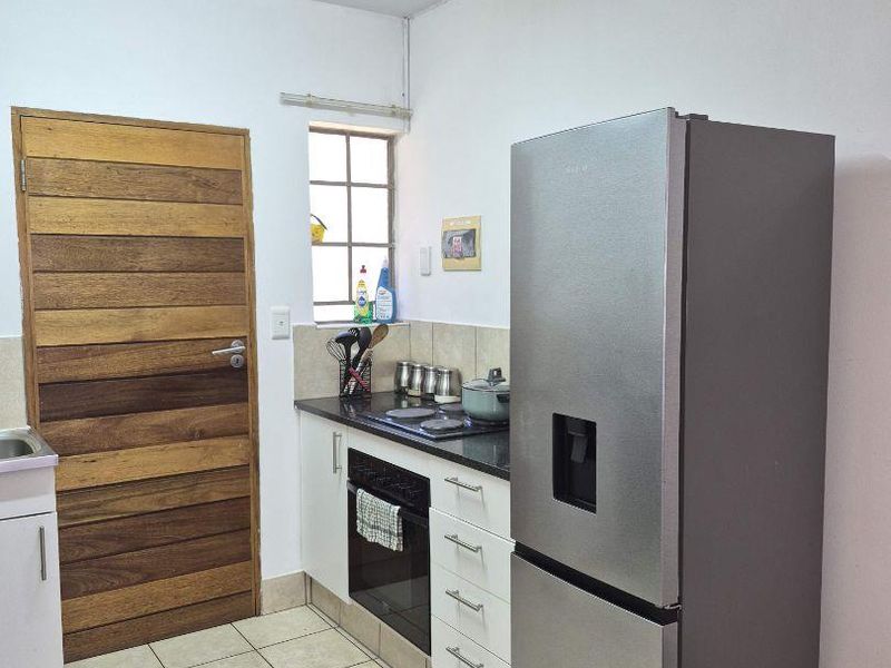A functional kitchen featuring white cabinetry, dark countertops, tiled flooring, and a built-in oven with hob.