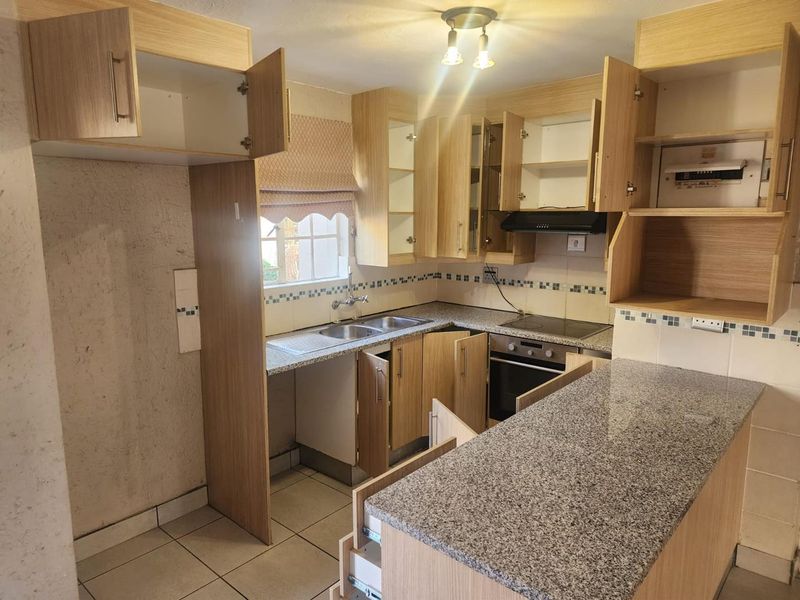 A dated kitchen featuring laminate cabinetry, granite countertops, and built-in appliances, currently requiring maintenance and cosmetic updates to improve functionality and aesthetic appeal.