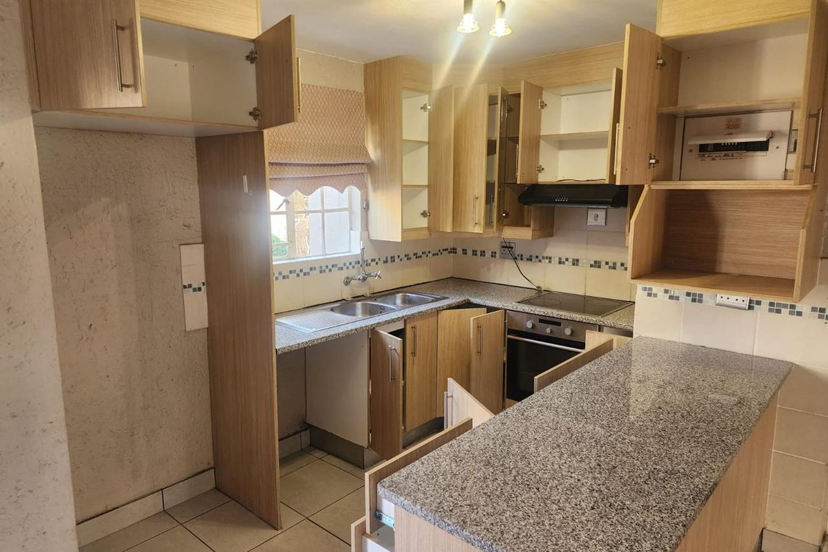 A dated kitchen featuring laminate cabinetry, granite countertops, and built-in appliances, currently requiring maintenance and cosmetic updates to improve functionality and aesthetic appeal.