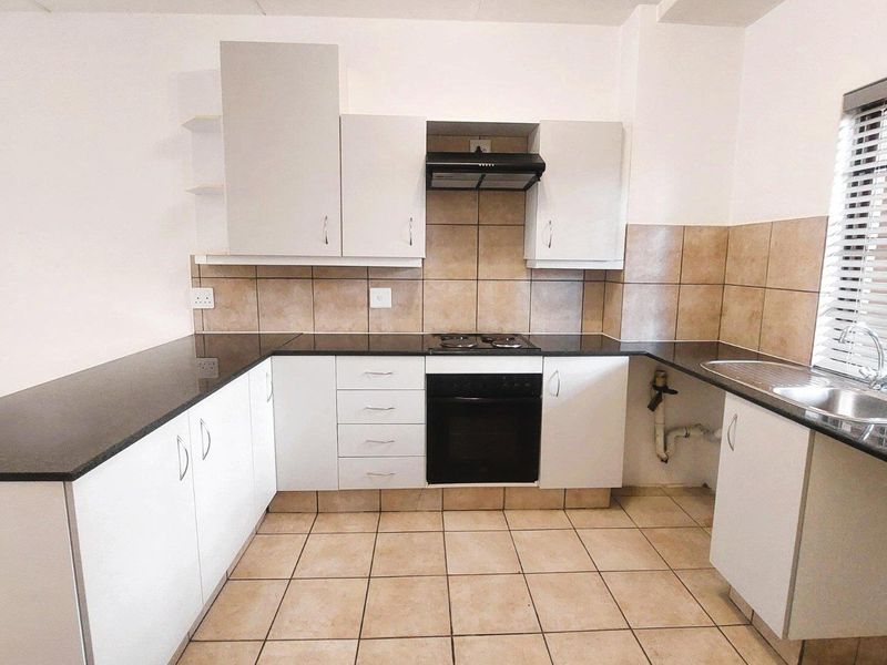 A functional kitchen featuring white cabinetry, dark granite countertops, built-in oven and hob, tiled backsplash, and tiled flooring.