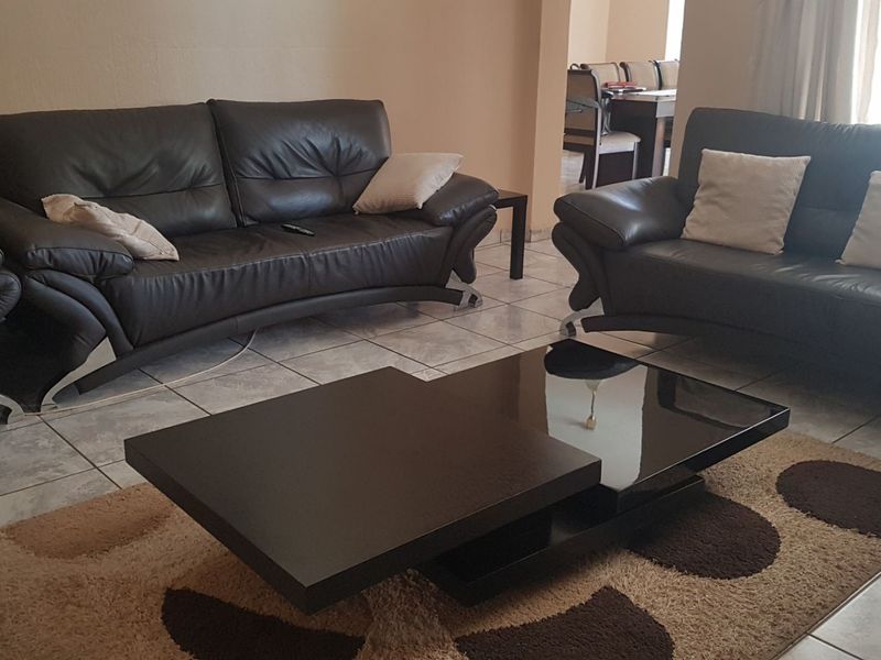 A spacious living area featuring neutral wall tones and light-colored ceramic floor tiles, providing a functional and open layout.