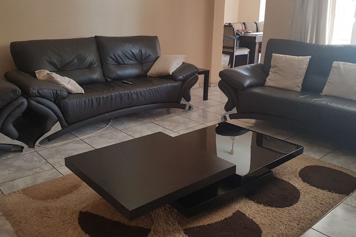 A spacious living area featuring neutral wall tones and light-colored ceramic floor tiles, providing a functional and open layout.