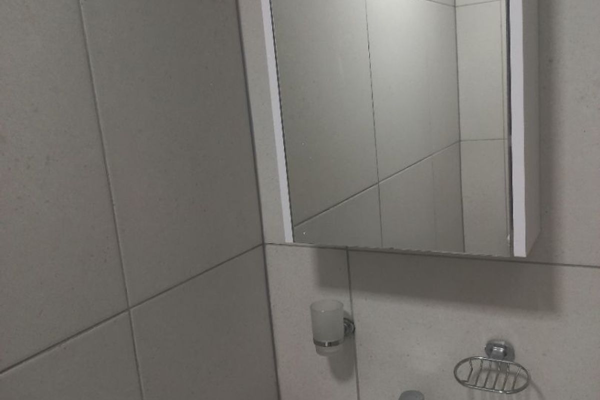 A clean and modern bathroom featuring a wall-mounted vanity mirror cabinet, ceramic basin with chrome mixer tap, and neutral wall tiling.