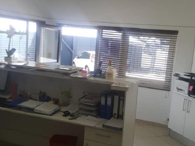 A functional office space featuring a built-in reception desk, tiled flooring, and suspended ceiling with integrated air conditioning.