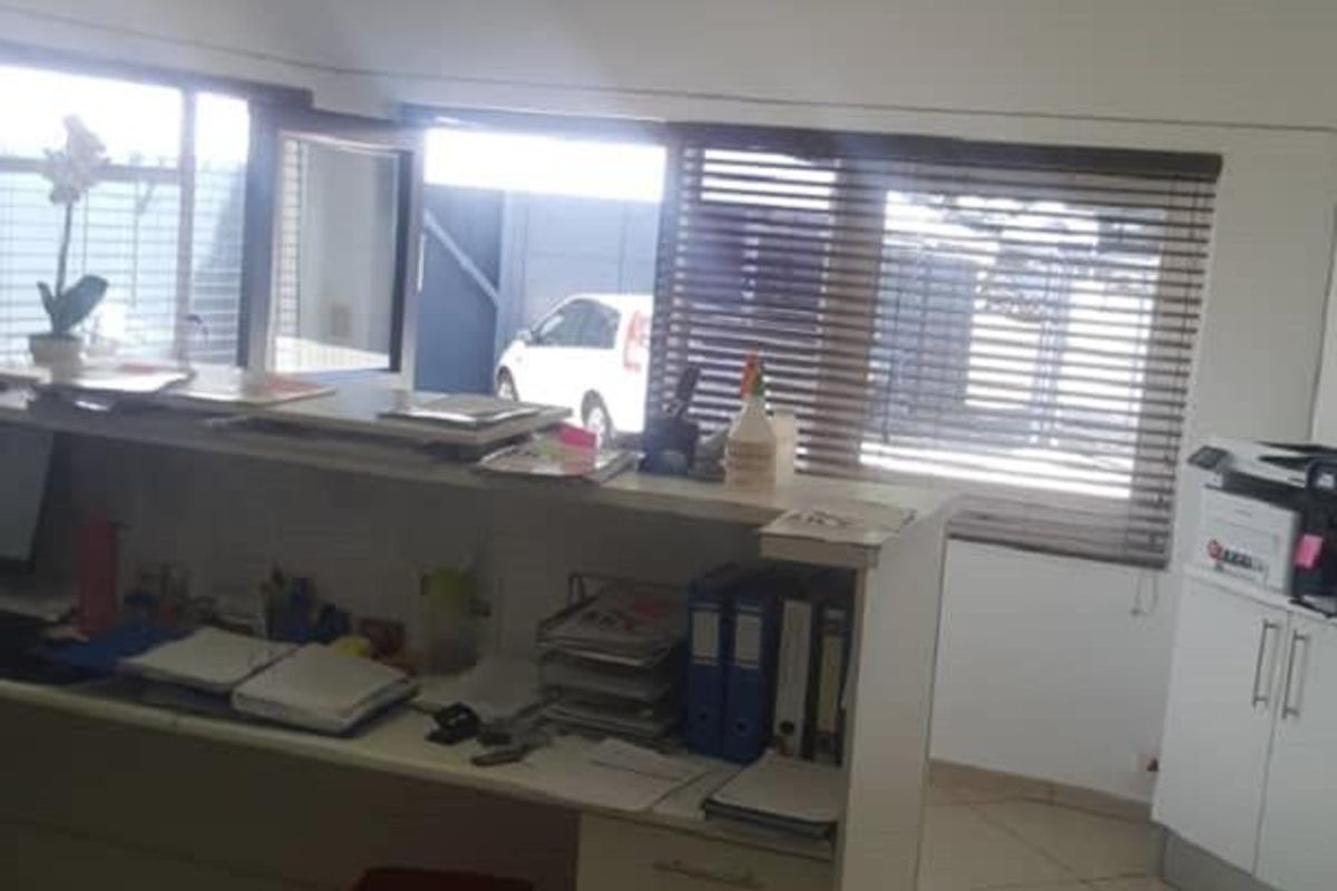 A functional office space featuring a built-in reception desk, tiled flooring, and suspended ceiling with integrated air conditioning.