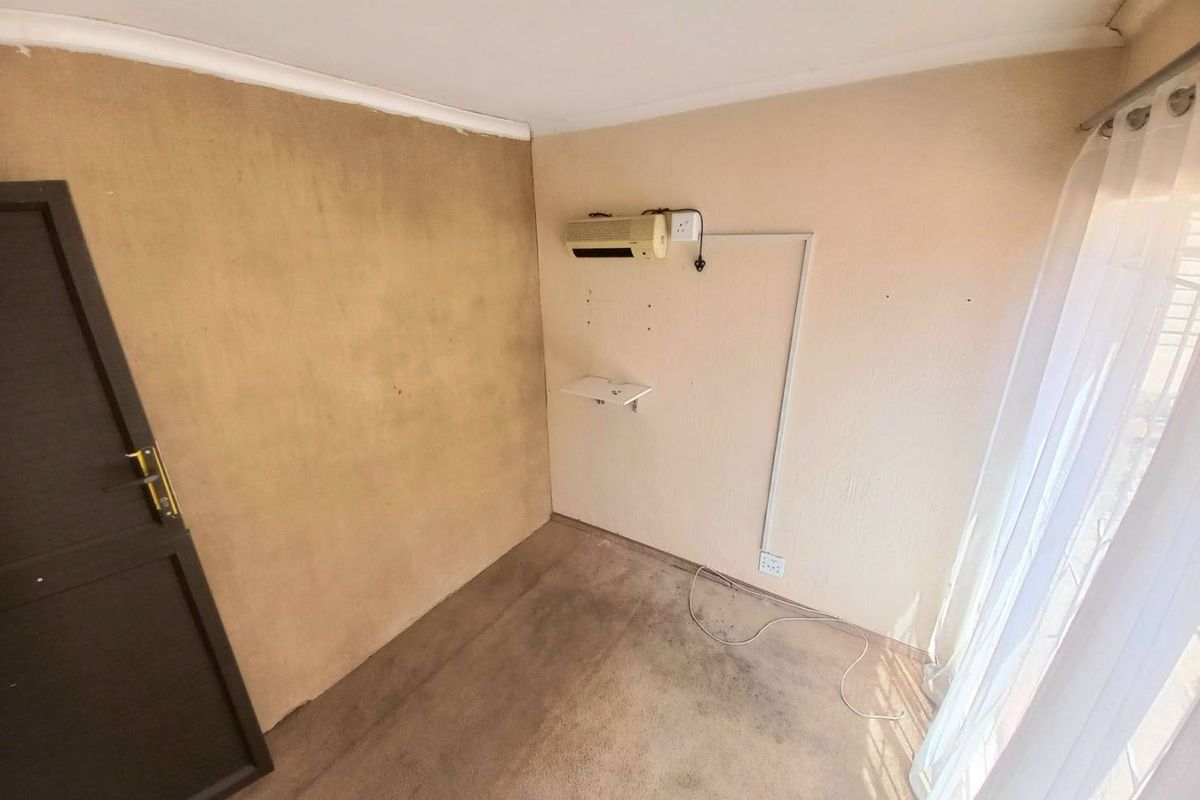 An empty bedroom featuring carpeted flooring, an air conditioning unit, and a sliding door with access to natural light.