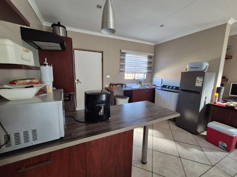 Functional kitchen featuring laminate countertops, built-in cabinetry, an extractor fan, and tiled flooring, offering a practical layout for daily meal preparation.