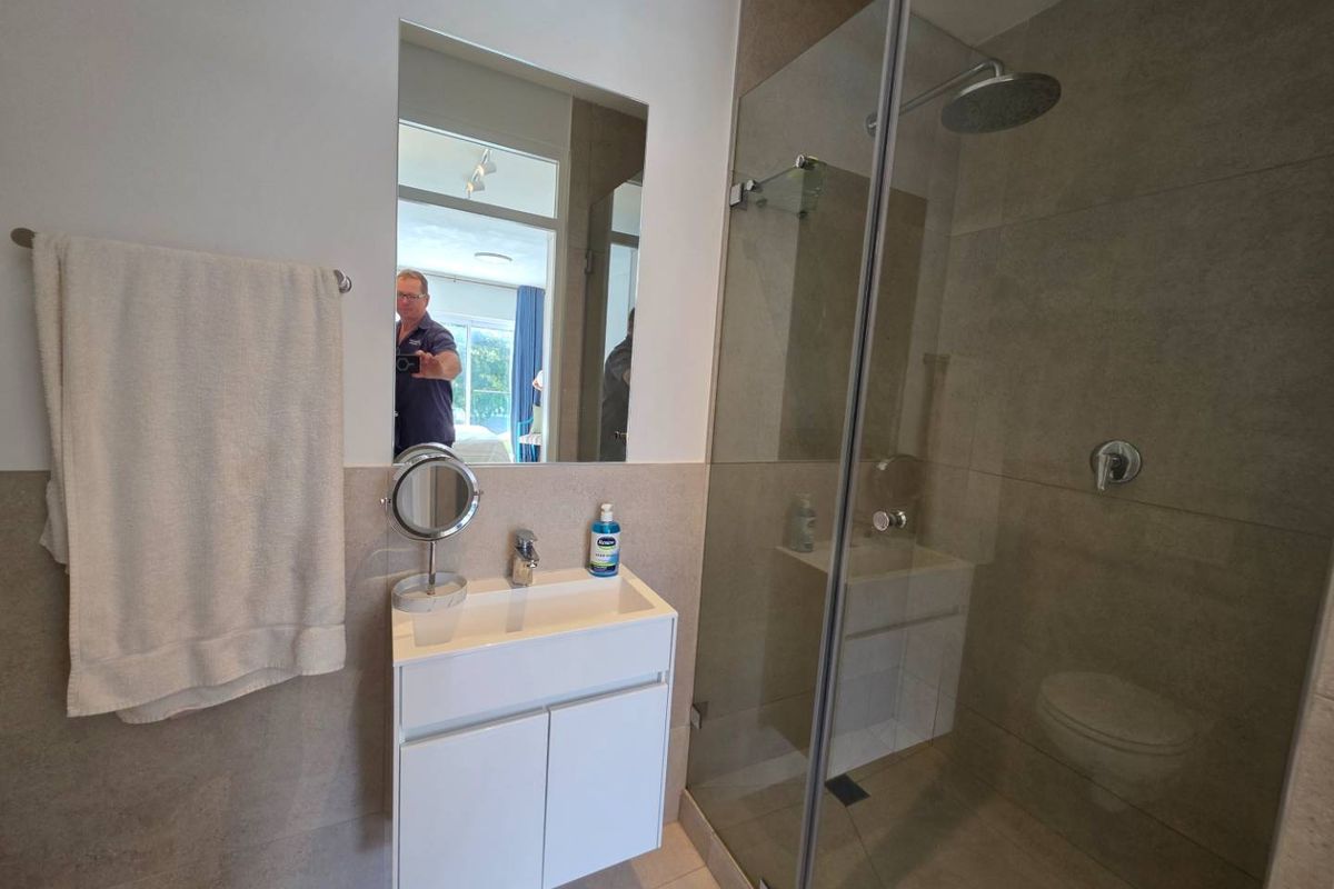 Modern bathroom featuring a wall-mounted vanity, basin, and a spacious walk-in shower with a rainfall shower head and frameless glass enclosure.