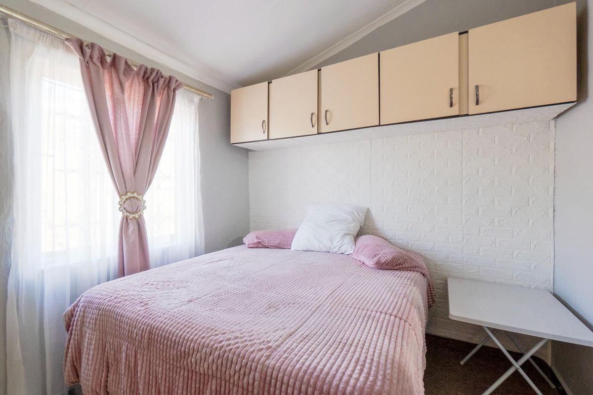A compact bedroom featuring built-in overhead storage cabinetry and a textured feature wall.