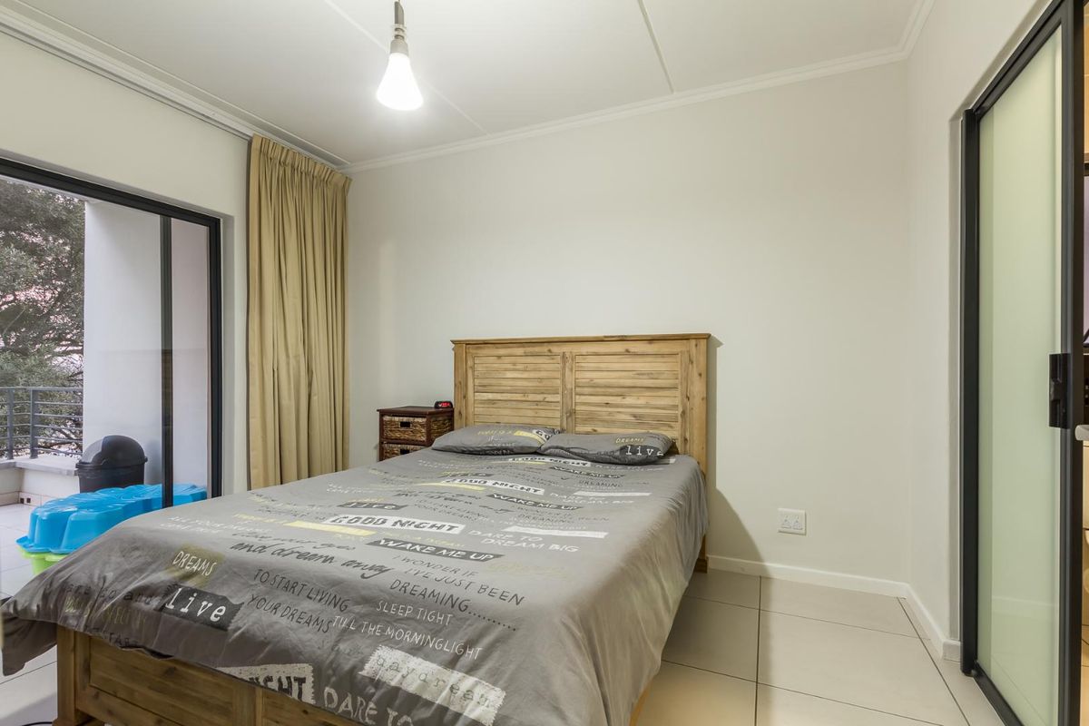 A bedroom featuring tiled flooring, a sliding glass door leading to a balcony, and a neutral color palette.