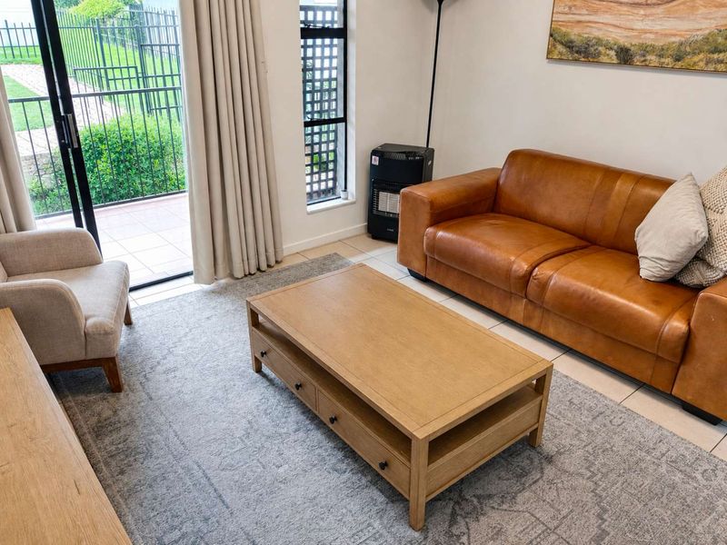 A bright living room featuring tiled flooring and a sliding glass door providing direct access to an outdoor patio area.