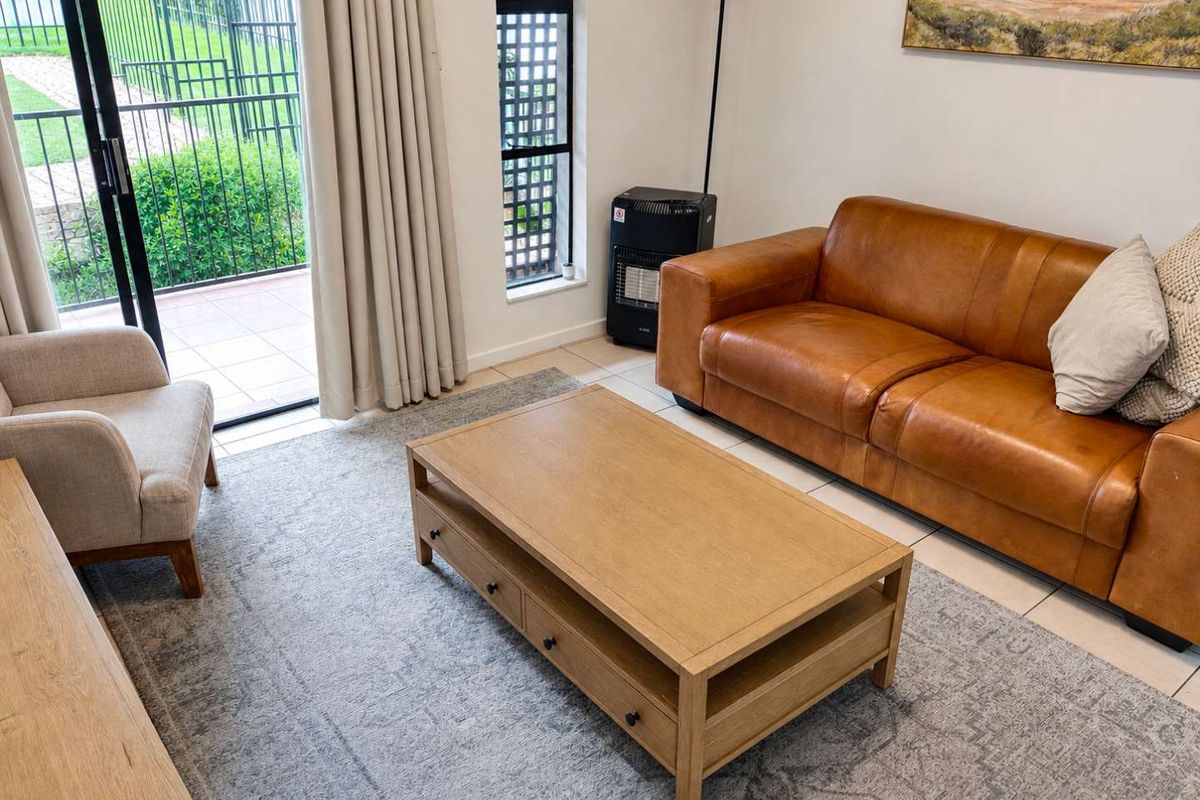 A bright living room featuring tiled flooring and a sliding glass door providing direct access to an outdoor patio area.