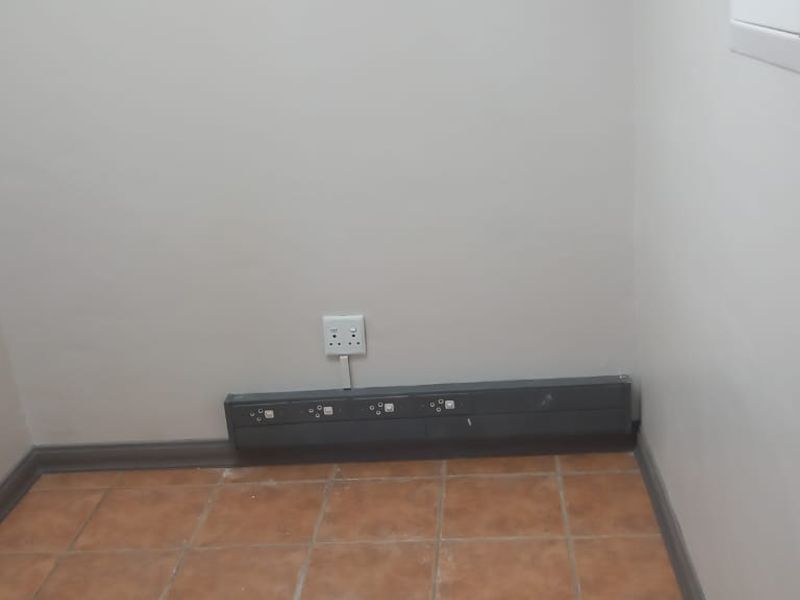 A small, empty office space featuring tiled flooring and integrated electrical power skirting for convenient workstation connectivity.