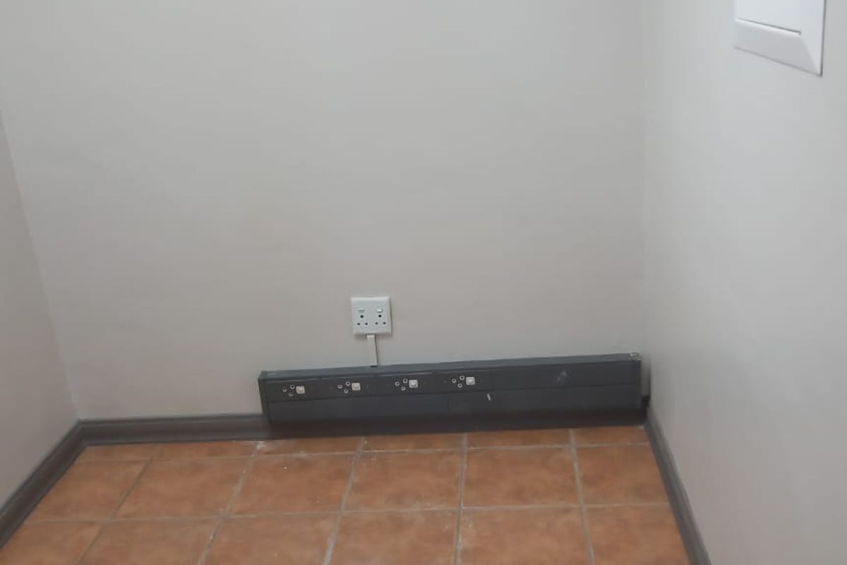 A small, empty office space featuring tiled flooring and integrated electrical power skirting for convenient workstation connectivity.
