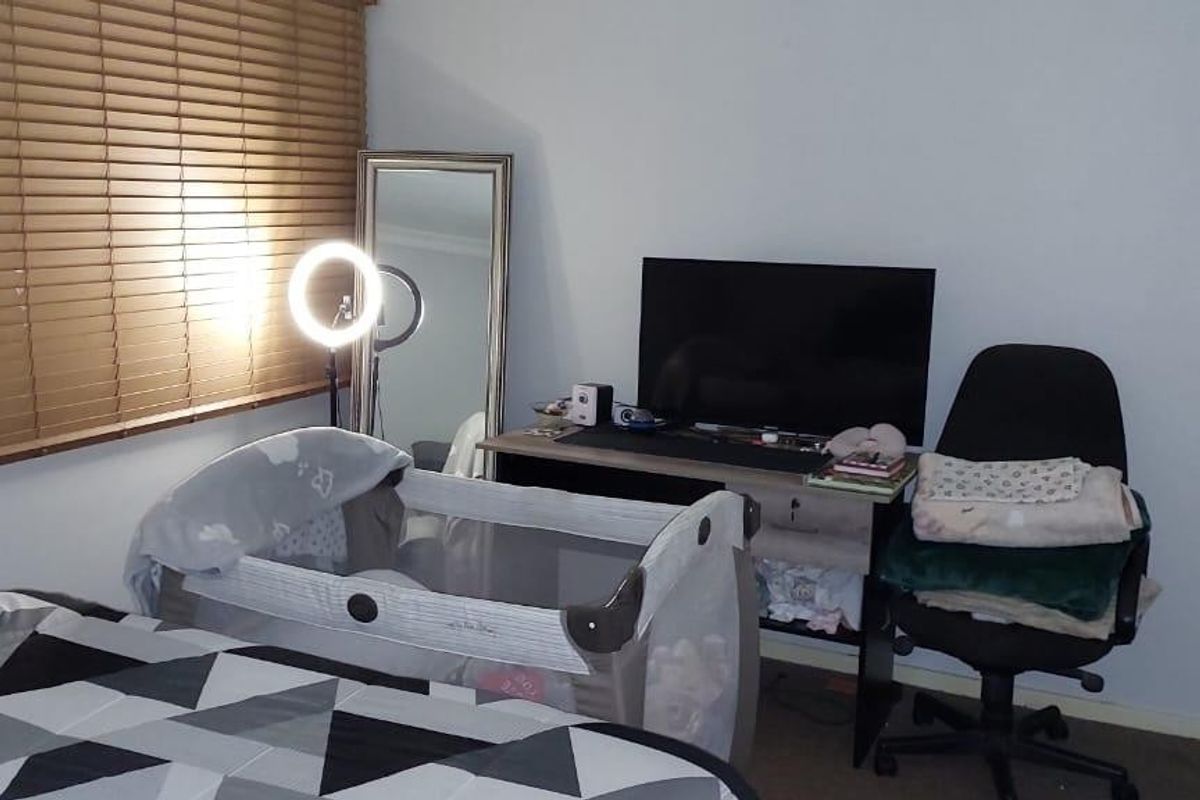 A bedroom featuring built-in wardrobes and venetian blinds, providing a functional space with neutral wall finishes.