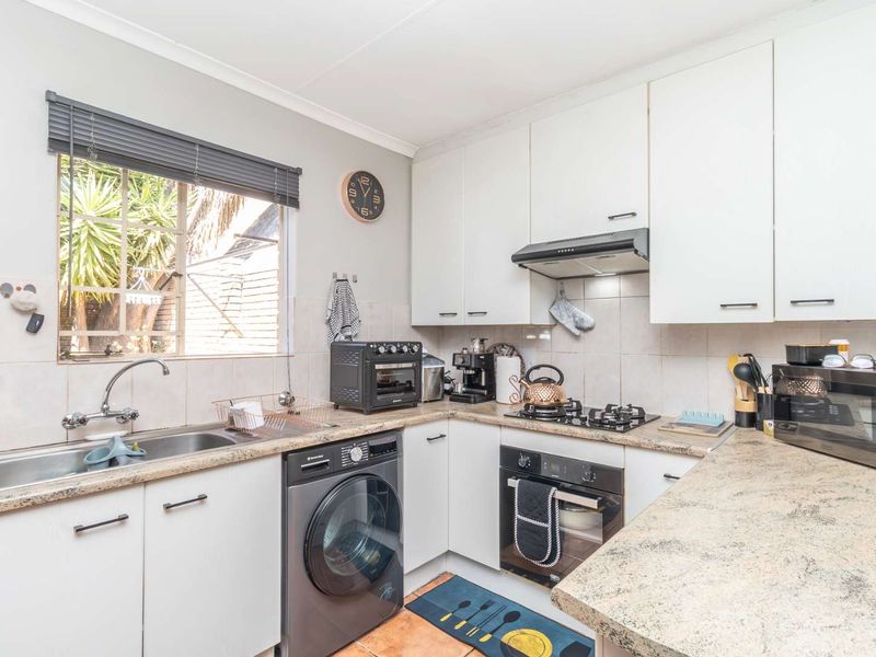 Functional kitchen featuring white cabinetry, laminate countertops, a gas hob, built-in oven, and integrated laundry plumbing.
