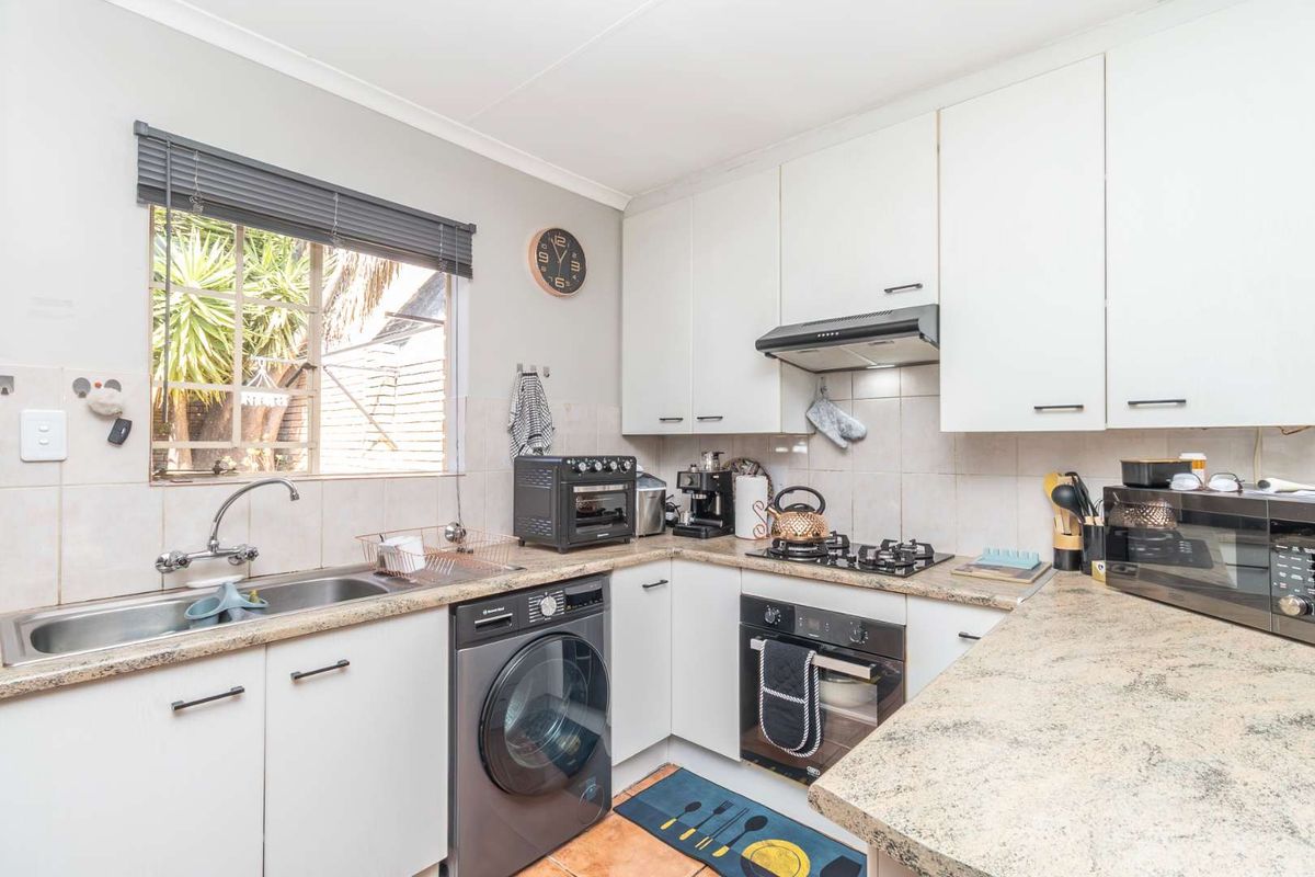 Functional kitchen featuring white cabinetry, laminate countertops, a gas hob, built-in oven, and integrated laundry plumbing.