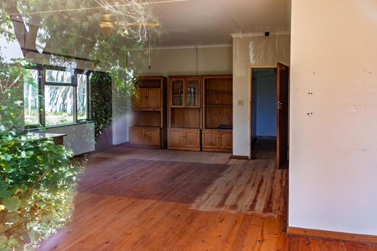 A living area featuring original timber flooring, built-in wooden cabinetry, and a ceiling fan, with direct access to an adjacent room.