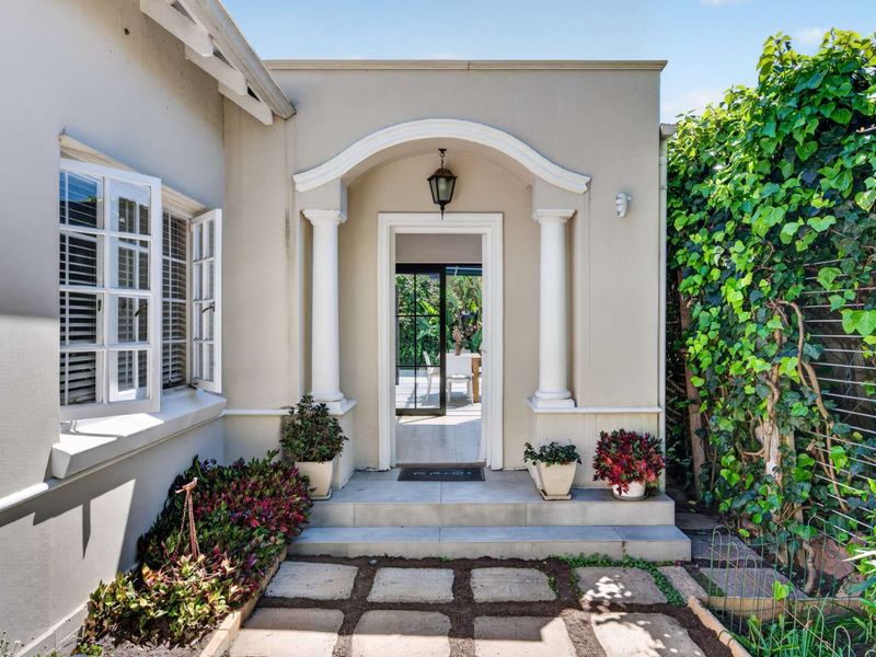 Charming front entrance featuring a classic arched portico with decorative columns, stone paving, and well-maintained exterior finishes.